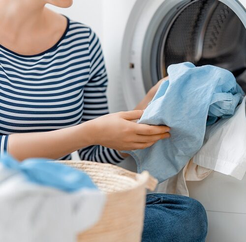 woman is doing laundry at home. laundry machine and hands close up